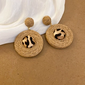 Détail de boucles d'oreilles en raphia tressé avec centre en tissu imprimé léopard