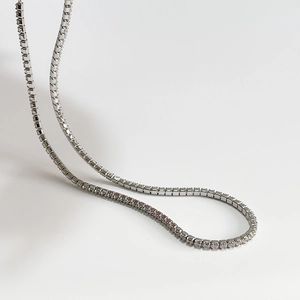 Minimalist silver tennis necklace with sparkling zircon crystals on grey background