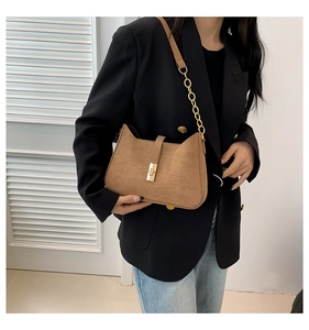 Detailed view of brown suede crossbody bag featuring a unique cat-ear silhouette and gold clasp