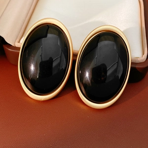 Close-up of vintage oval resin earrings with matte gold trim on silk background