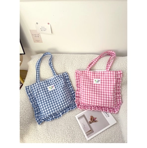 Detail of blue and pink plaid tote bags with ruffle edges and fun fun party label