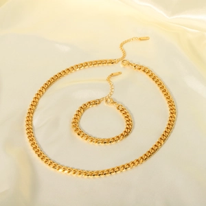 Detailed view of 18K gold plated Cuban chain necklace and bracelet on silk fabric