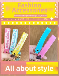 Close-up of silicone wristband with Good Luck text, bell, and metal key ring accessory