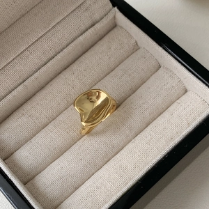 Macro shot of irregular lava textured gold ring presented in a cream jewelry box