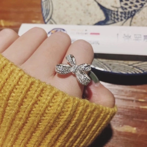 Close-up of a silver bow ring with shimmering stones worn on a hand over a dining setting