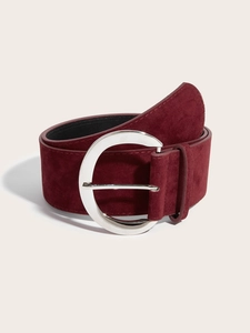 Détail d'une large ceinture en daim bordeaux avec une grande boucle ronde en métal argenté