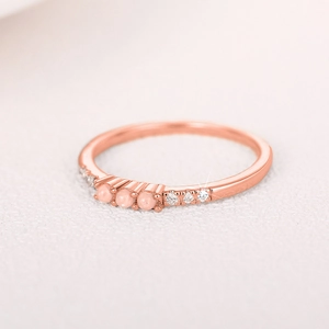 Makroaufnahme eines Roségoldrings mit drei rosa Opalen und Diamantakzenten