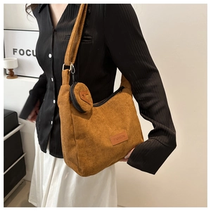 Close-up of brown corduroy crossbody bag with a round coin purse and FASHION label