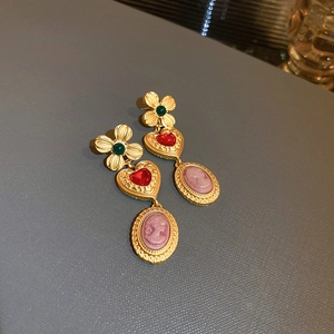 Close-up of vintage flower earrings with green stones and cameo portrait pendants
