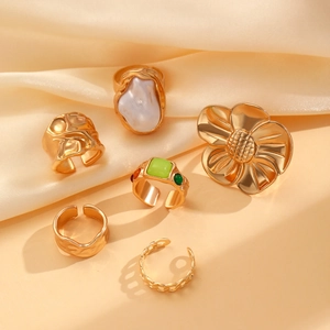 Detail view of 6-piece gold flower ring set with pearls and gems on silk fabric