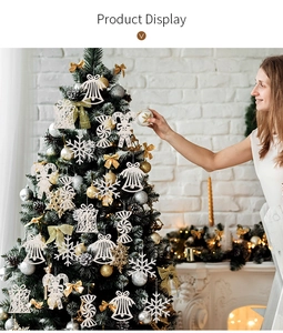 White Christmas ornaments featuring snowflakes and bells hanging on a festive tree branch