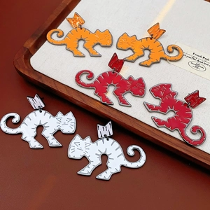 Detailed view of cute cat stud earrings in orange, red, and white on a wooden tray