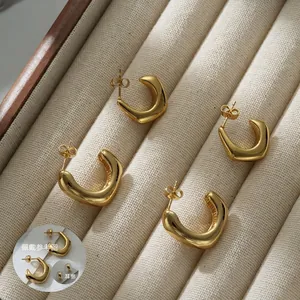 Polished 18k gold-plated stainless steel geometric C-shape hoop earrings on beige velvet