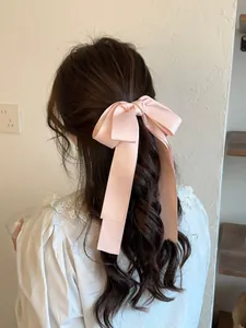 Barrette à cheveux avec nœud en satin rose portée sur une queue de cheval