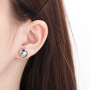 Close-up of minimalist silver sphere stud earrings on model for visual scale