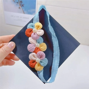 Detailed view of baby elastic headband with three colorful plush flowers and pearls