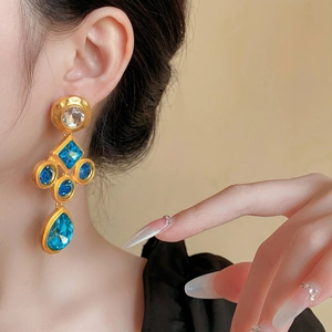 Vintage gold drop earrings with teardrop blue crystals and geometric hammered metal texture