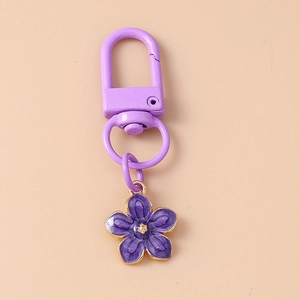 Detail of purple cherry blossom keychain with golden metal trim and matching purple clasp