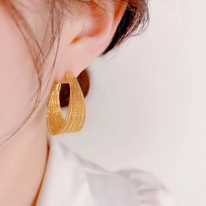 Close-up of golden multi-layer textured hoop earrings with a fine metallic silk finish