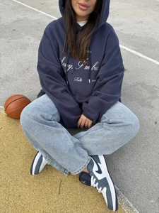 Λεπτομέρεια από oversized σκούρο μπλε φούτερ με κουκούλα και λευκό τύπωμα κειμένου