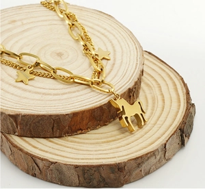 Détail du bracelet double couche doré avec breloques licorne et étoile sur bois