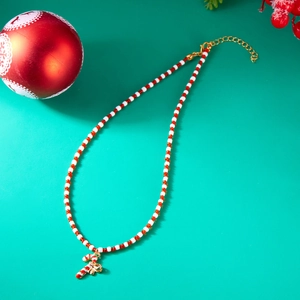 Detail of Christmas beaded necklace featuring a candy cane pendant on green background