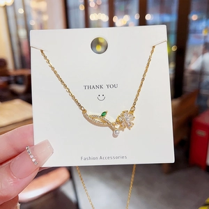 Elegant gold flower necklace with pearl and zircon pendant on a white display card