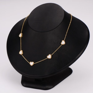 Golden heart necklace set with white mother of pearl pendants on a black bust display