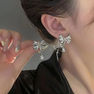 Close-up of bowknot earrings with pearls and teardrop crystals worn by a model