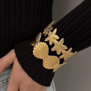 Golden stainless steel starfish and seashell bracelet set worn on a model wrist