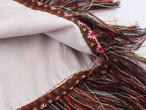 Detail shot of multicolor tassels and geometric embroidery on ethnic style mini skirt