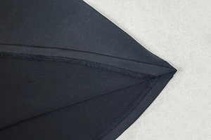 Detailed close-up of double-stitched seams on a premium black knit evening maxi dress