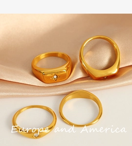 Detailed view of four 18k gold plated stainless steel rings with zircon stars on silk cloth