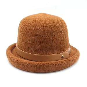 Detail of caramel knit fisherman hat featuring a leather strap and golden stud accent