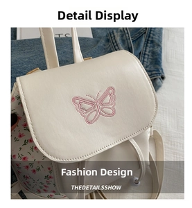 Detail of white mini backpack featuring pink butterfly embroidery and floral side patterns