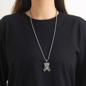 Detail of a silver bear pendant on an O-chain necklace worn by a model on black fabric