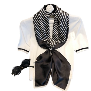Chic black and white striped silk square scarf styled on a white short-sleeve knit sweater
