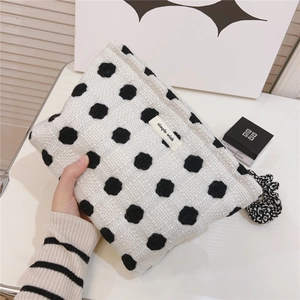 Gros plan sur la trousse de maquillage en tricot à pois noirs et étiquette simple wish