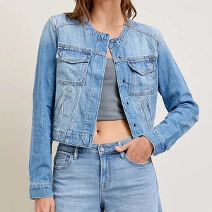 Close-up of light blue denim jacket showing collarless design and metal button details