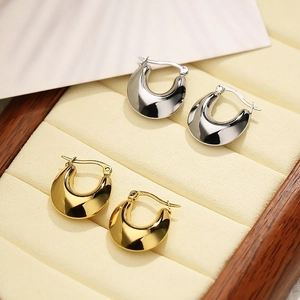 Polished chunky U-shaped hoop earrings in gold and silver finish displayed in jewelry box