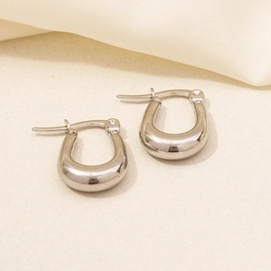 Macro shot of silver U-shaped hoop earrings with a polished minimalist metal finish