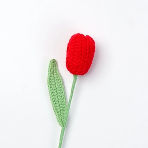 Makroaufnahme einer handgefertigten roten Häkel-Tulpe aus Garn mit grünen Blättern