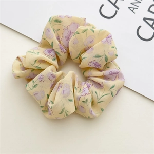 Close-up of chiffon floral scrunchie featuring purple flowers on a yellow fabric base