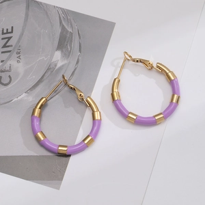 Detail of light purple enamel and gold titanium hoop earrings on a fashion magazine