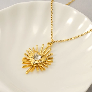 Collier doré avec pendentif cœur rayons de soleil et zircon sur plateau coquillage