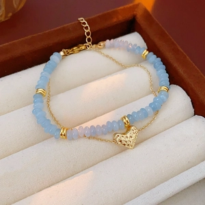 Close-up of double-layered heart pendant necklace with light blue beads and golden chain
