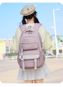 Outdoor view of a purple canvas backpack with adjustable straps and hanging ornaments