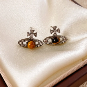 Vue détaillée des boucles d'oreilles Saturne argentées avec pierres ambrées sur satin