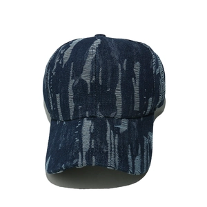 Detailed top view of distressed denim baseball cap with blue washed patterns and ripped style