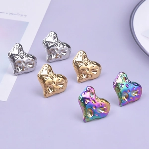 Detailed macro view of heart-shaped stainless steel earrings with hammer-textured metal finish